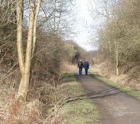 Two people walking along a railway path